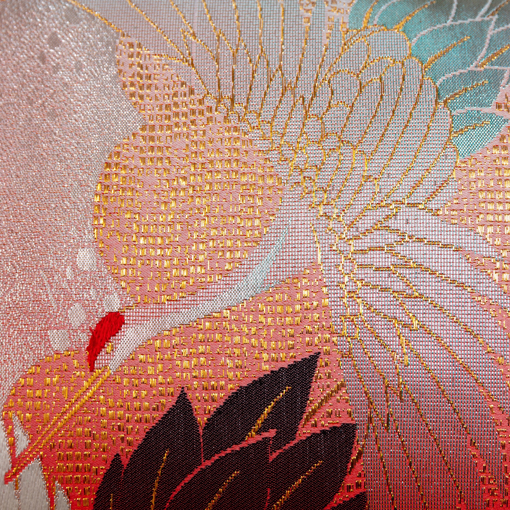 Detail of a japanese kimono pillow showing flying crane woven in pale blue metallic thread over a red silk base.