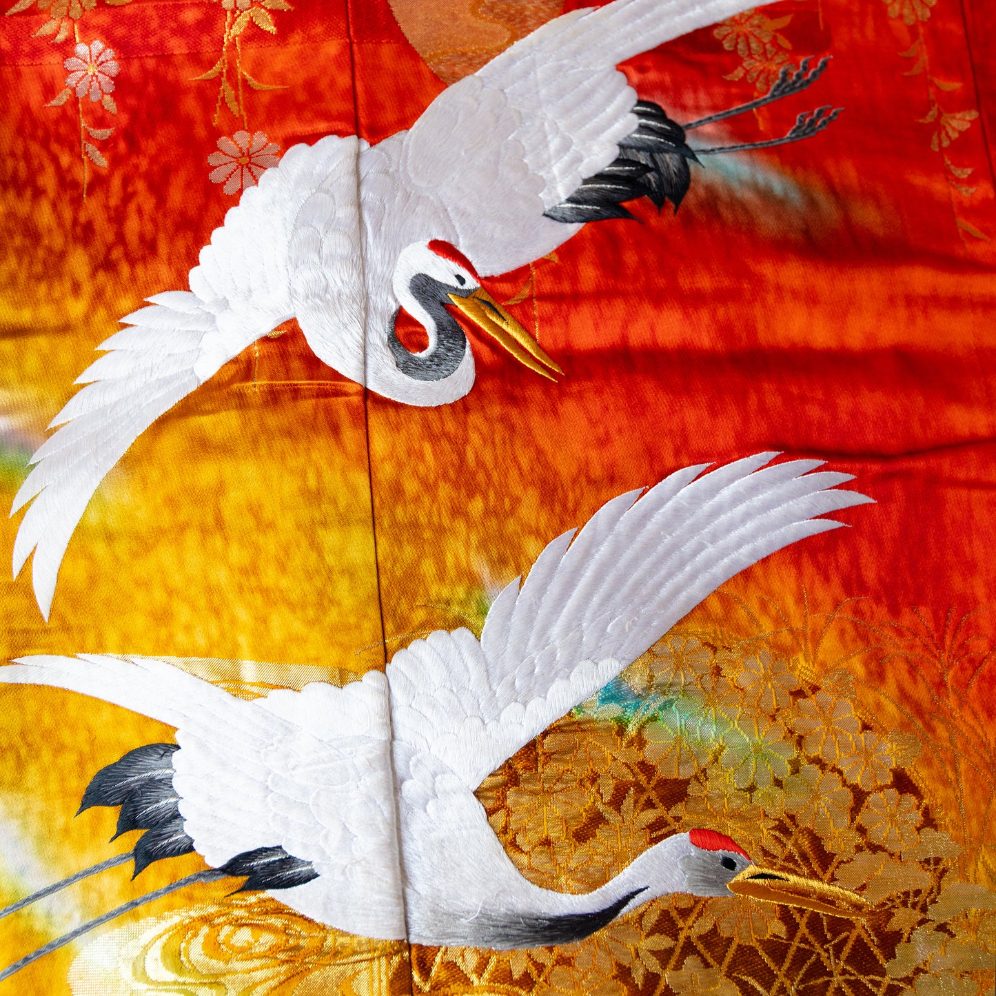 Oriental silk throw blanket with flying cranes over red and gold.