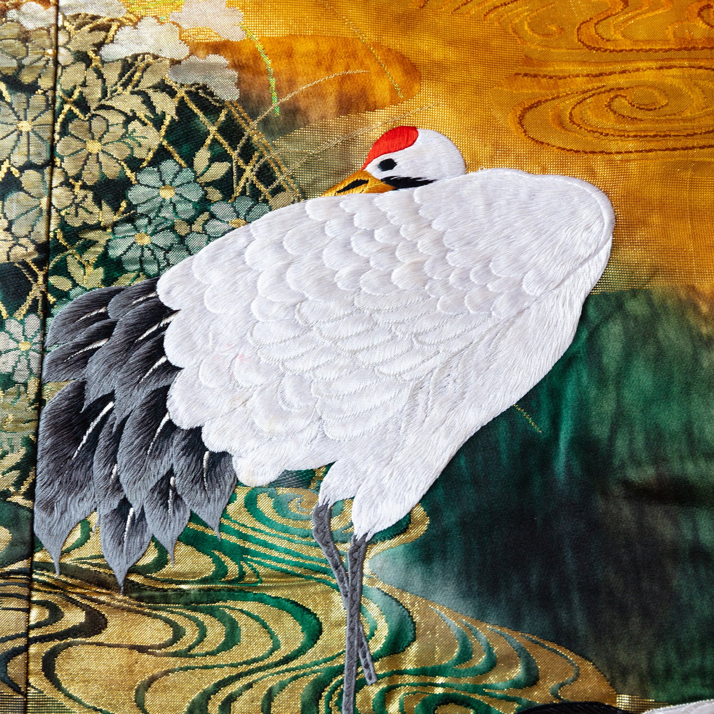 Red, gold and green silk throw blanket with white embroidered cranes.