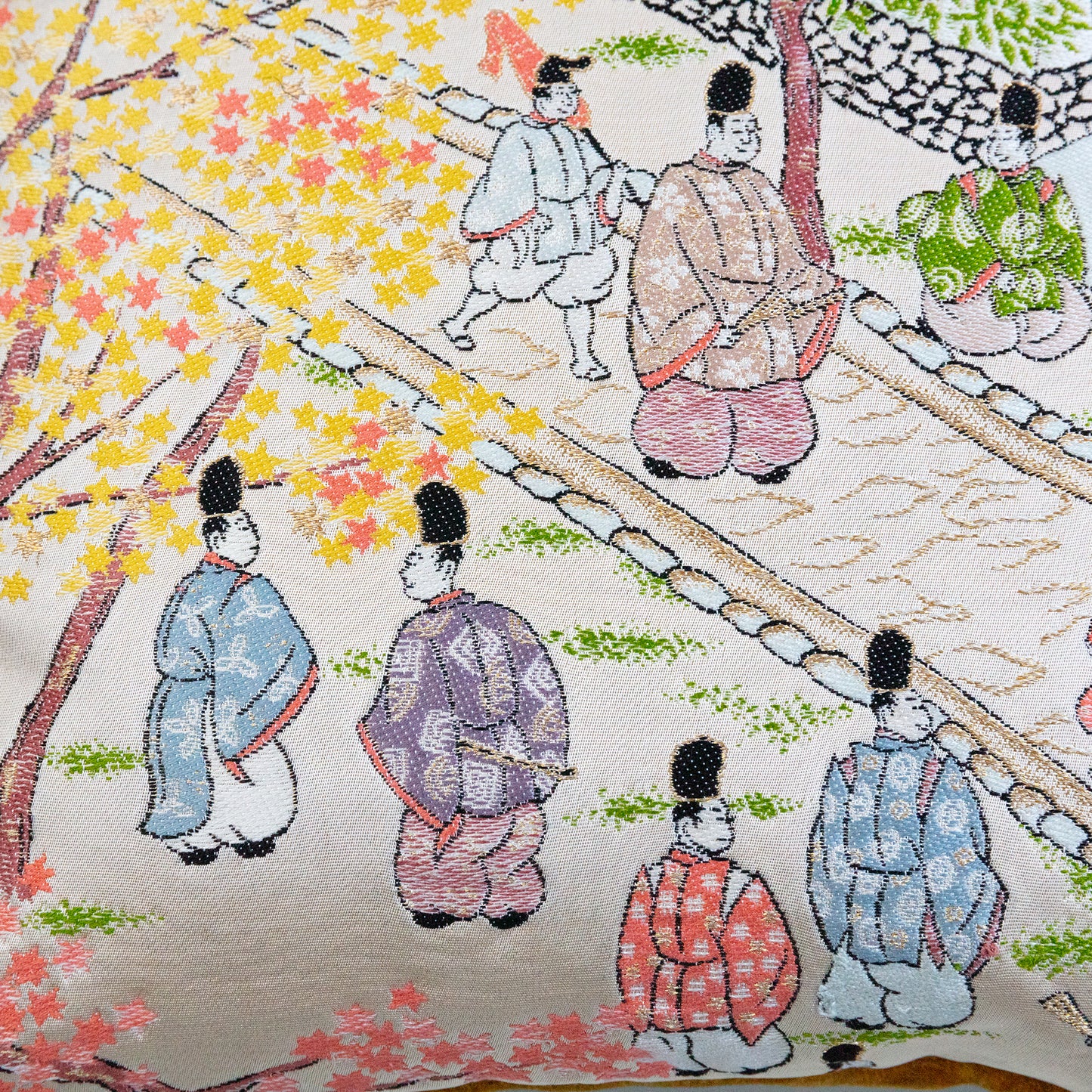 Detail of the obi pillow design showing japanese figures in a street scene on gold silk.