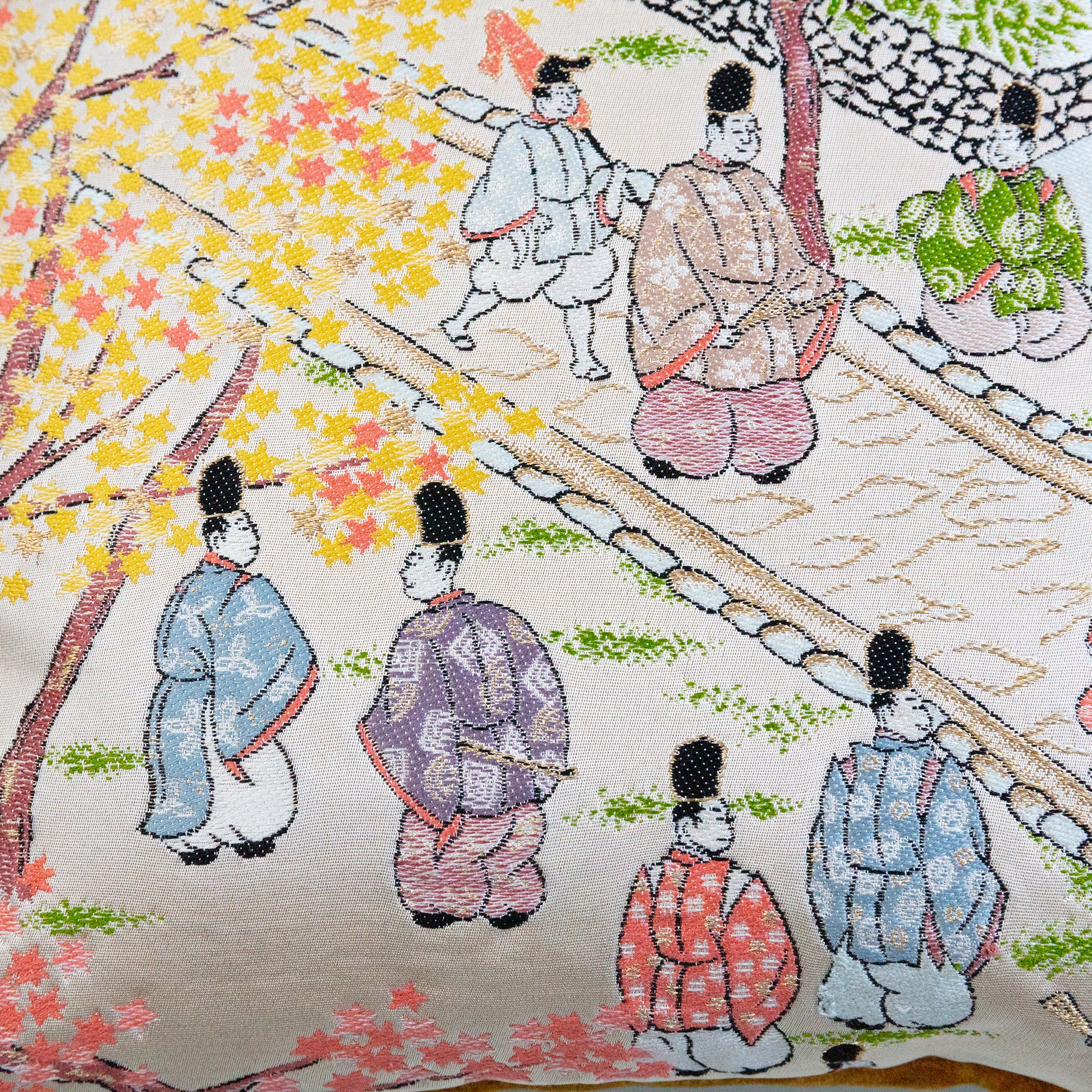 Detail of the obi pillow design showing japanese figures in a street scene on gold silk.