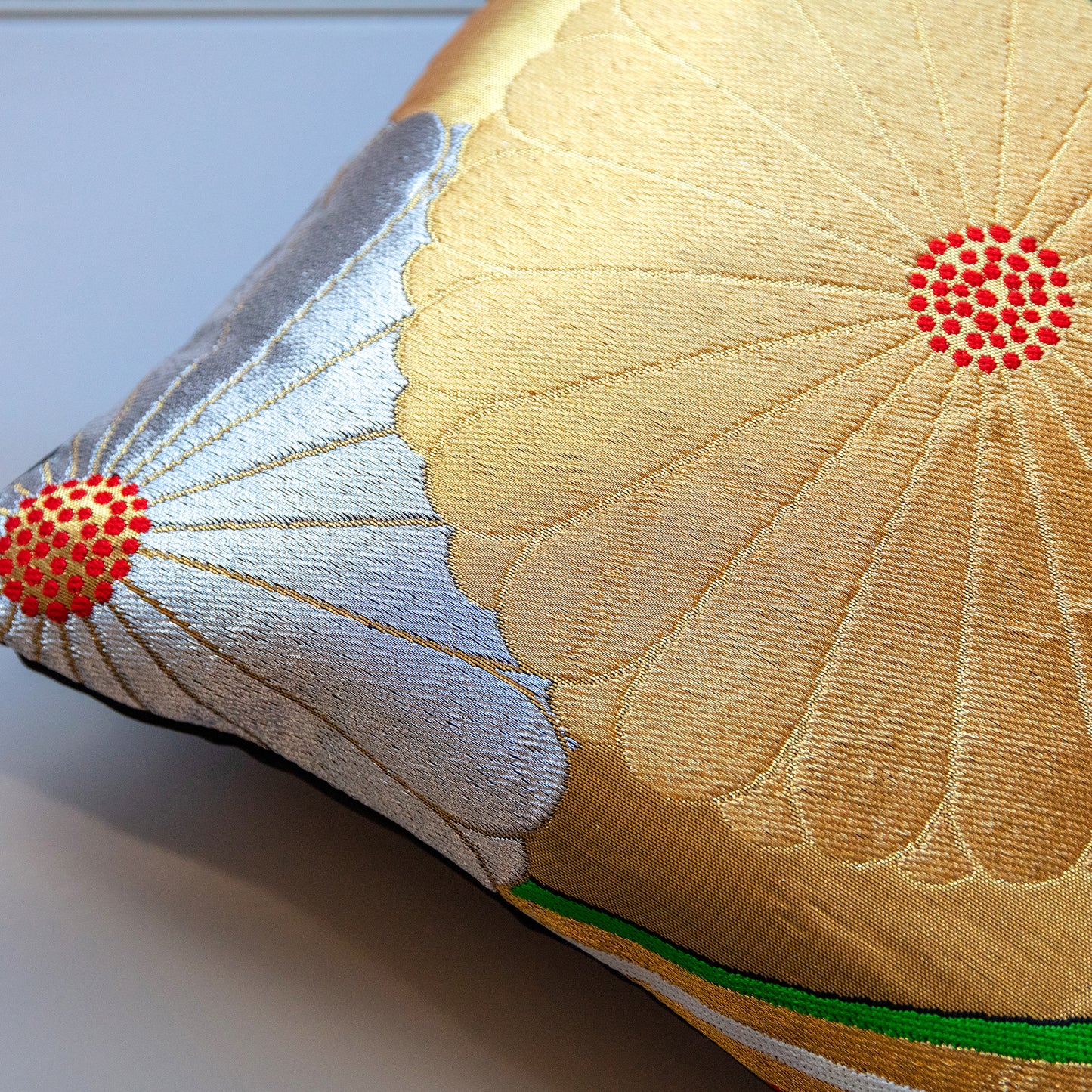 Gold obi pillow with silver and gold flowers design, close up of one corner.