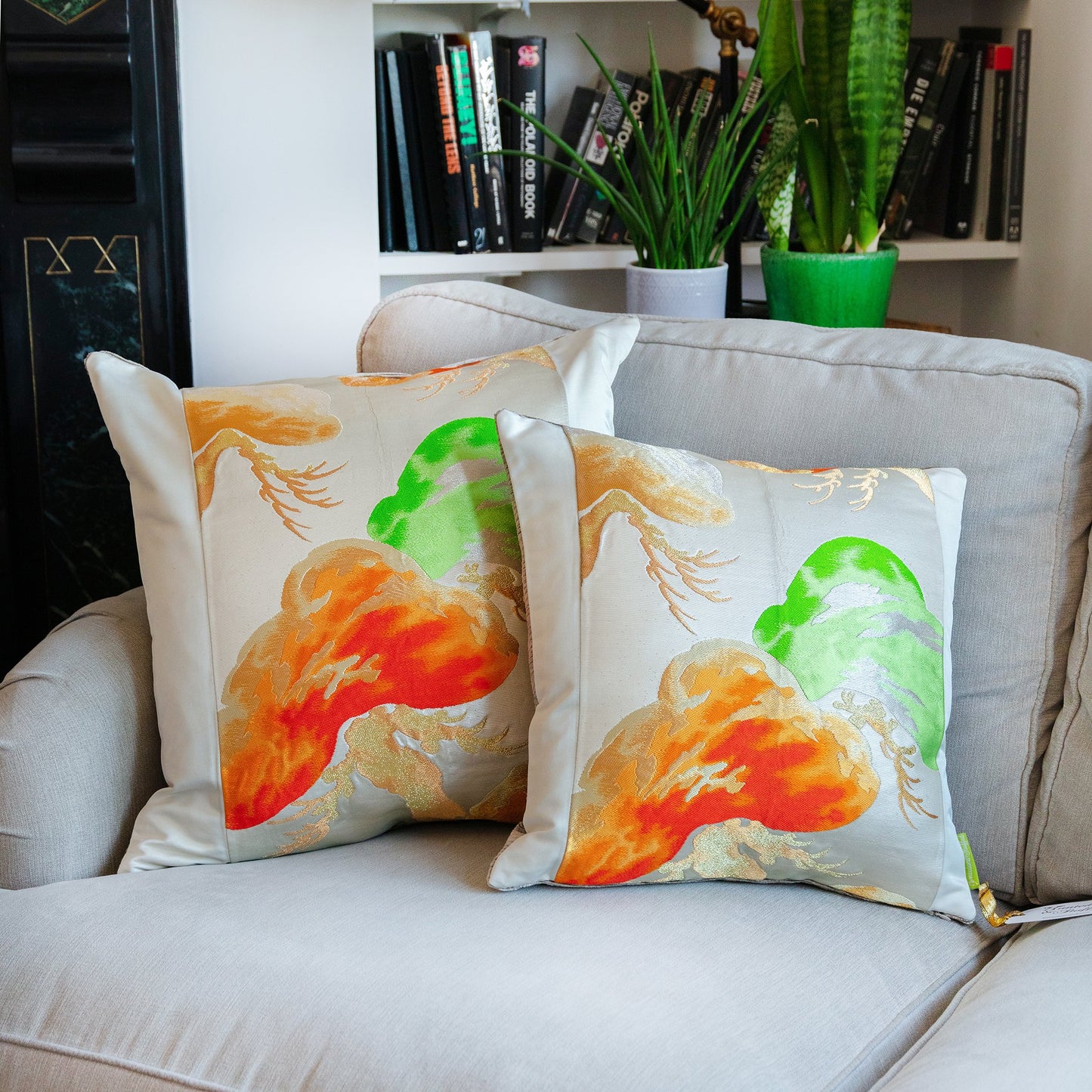 Large and medium sized cream throw pillows side by side on a couch.
