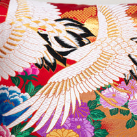 uchikake pillow detail of flying white cranes over colourful flowers, embroidery on silk.