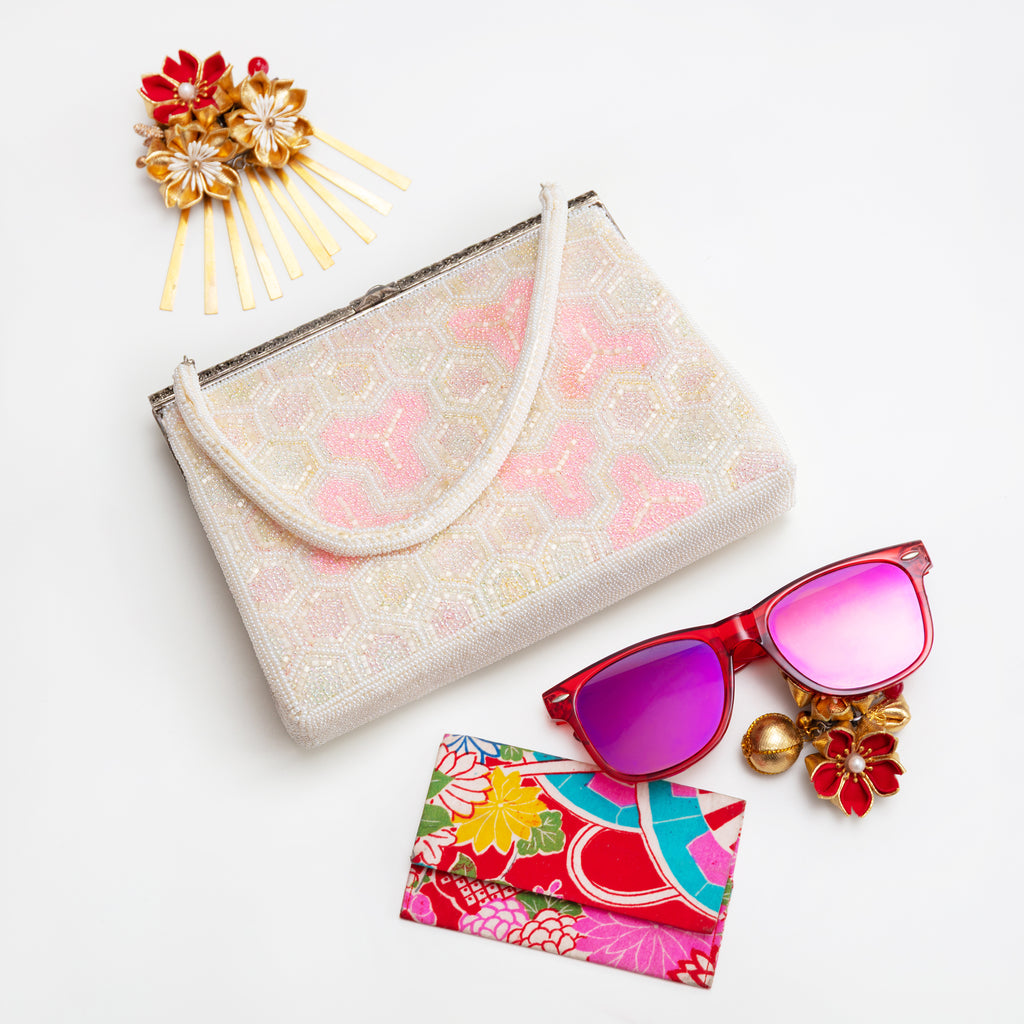 Close-up of intricate pink and white beadwork detailing on the clutch’s decorative floral pattern at its side edge.