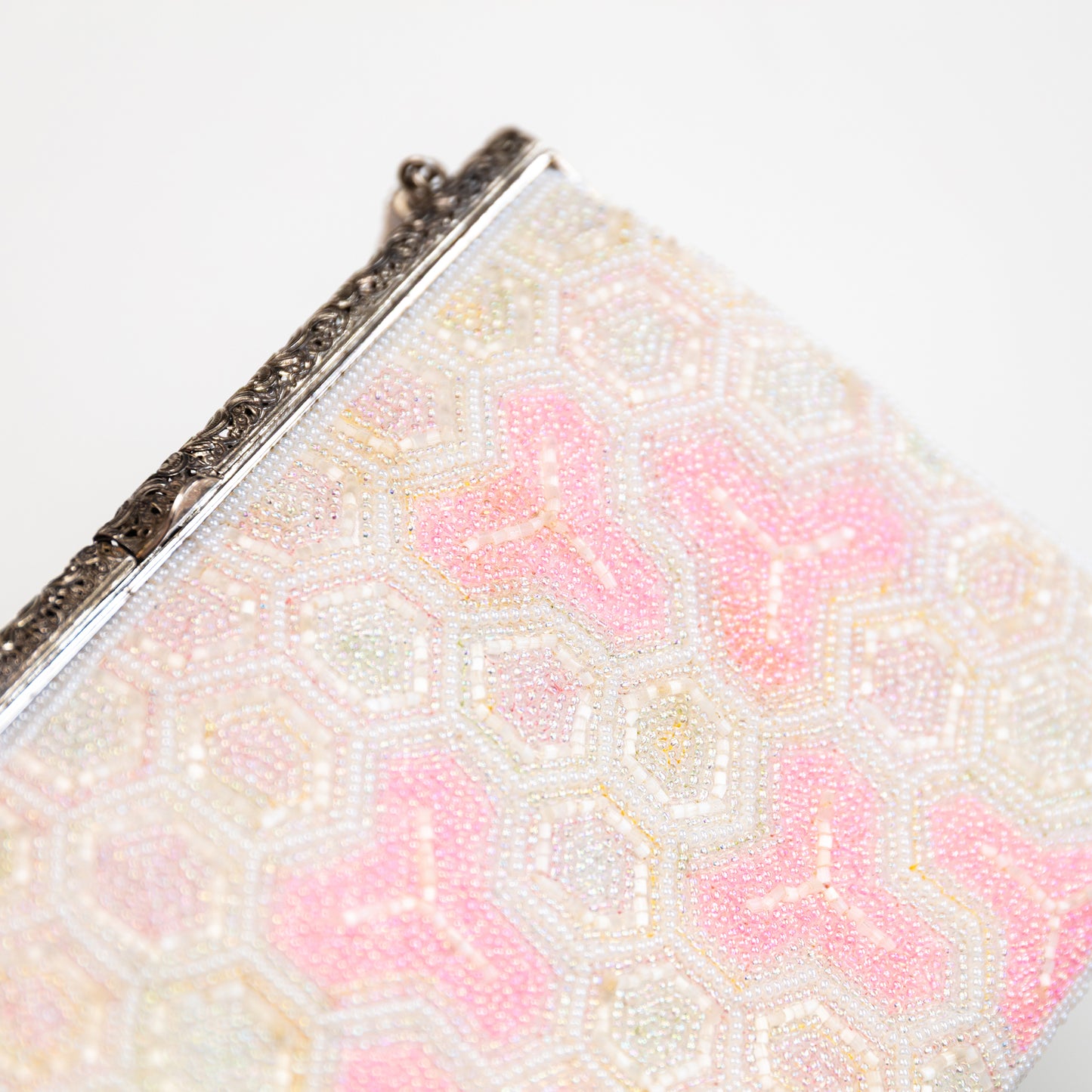 Close-up of a beaded clutch with pink and white pattern on a light background