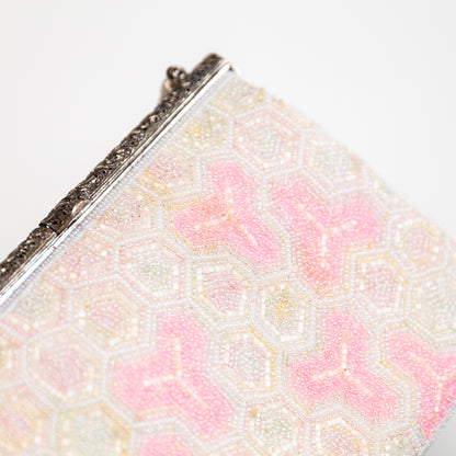 Close-up of a beaded clutch with pink and white pattern on a light background