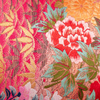 Close-up of the pink ombre fabric showcasing delicate crane and floral embroidery on purple velvet bolster cushion side