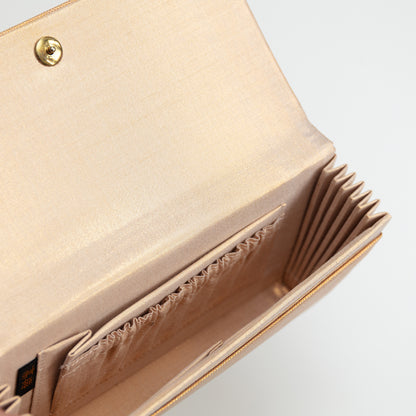 Detail of inside the gold envelope clutch with metallic gold and beige lining silk, internal pockets and gold metal closing stud on white background.