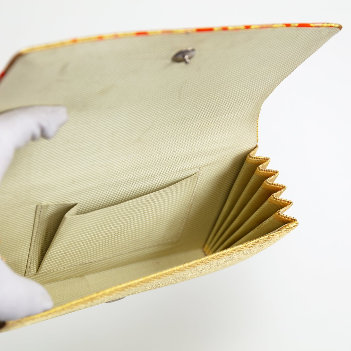 Close-up of a interior of gold clutch bag with a textured surface on a white background