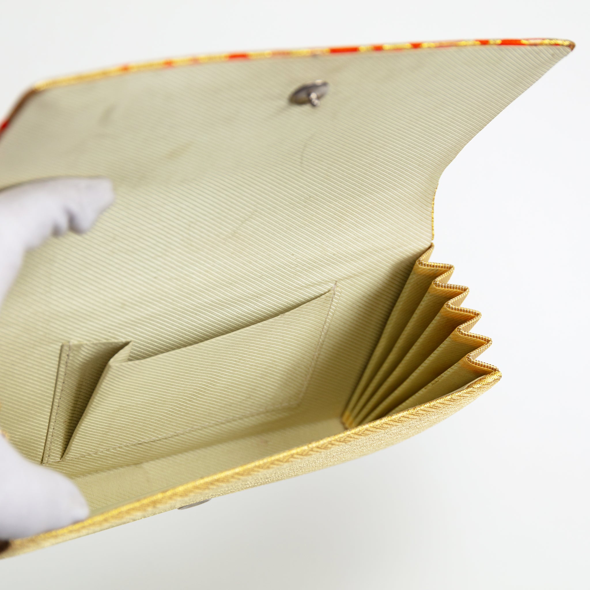 Close-up of the clutch’s textured gold silk surface highlighting orange diamond patterns and intricate stitching detail