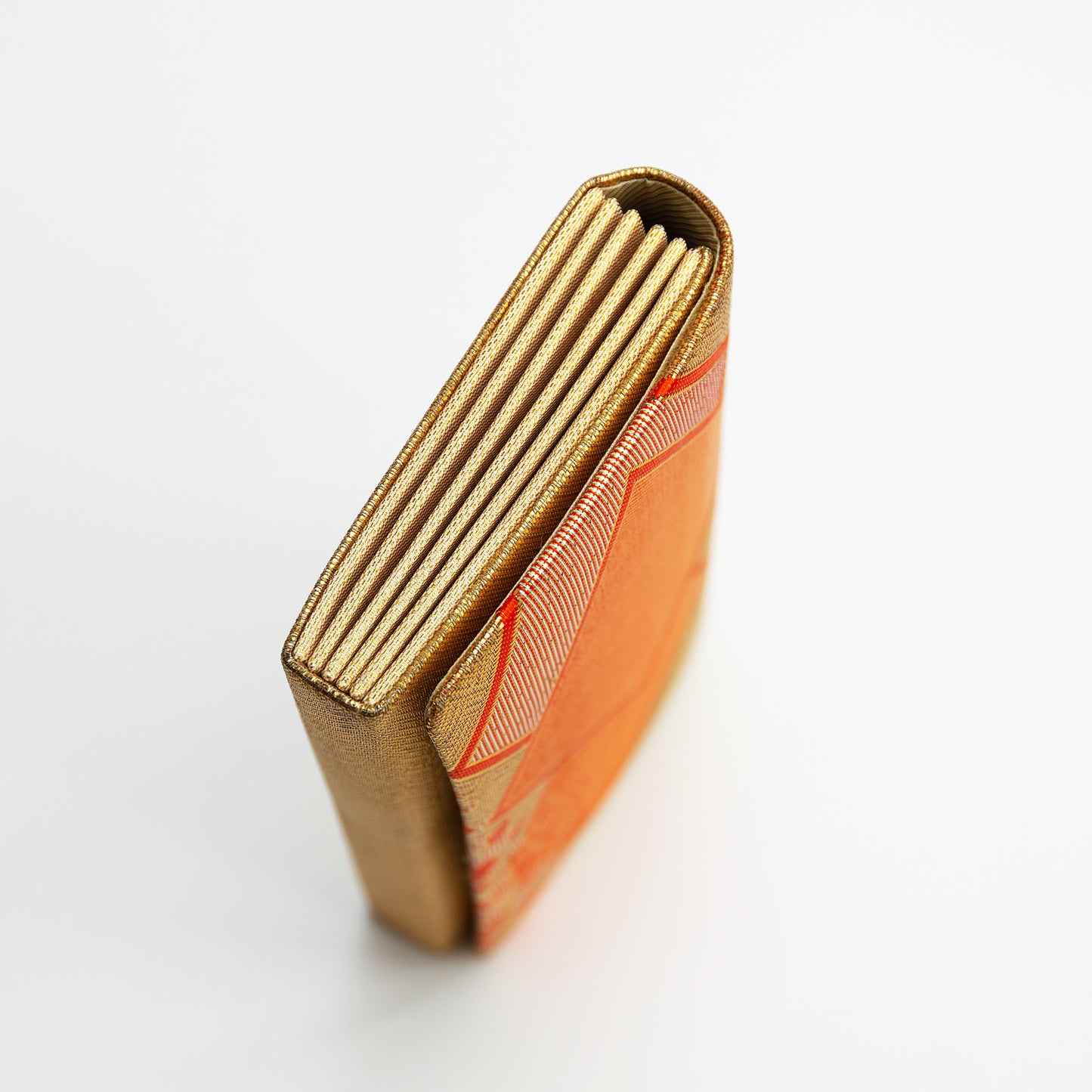 Side view of the gold metallic envelope clutch bag, vintage Japanese brocade on white background.