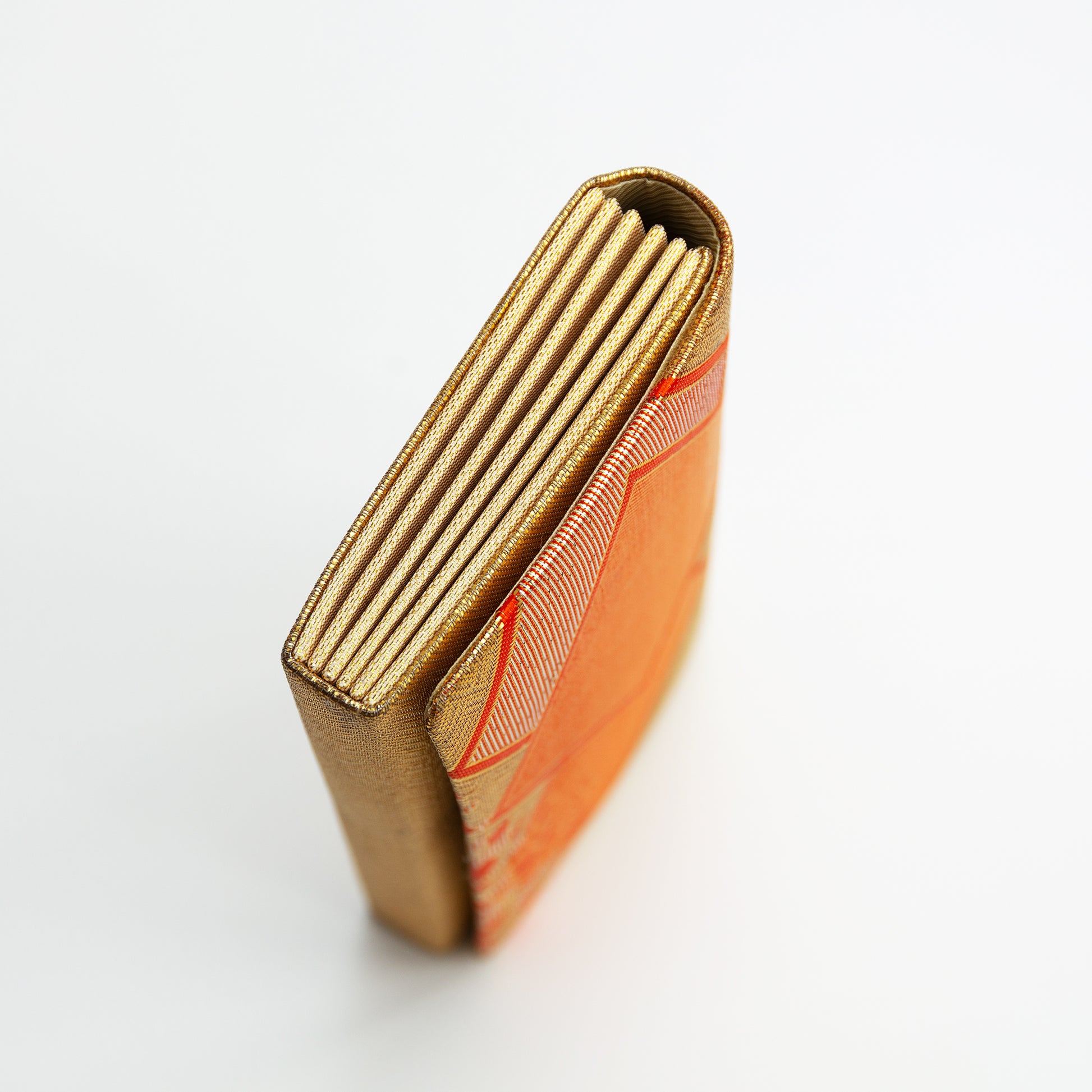Side view of the gold metallic envelope clutch bag, vintage Japanese brocade on white background.