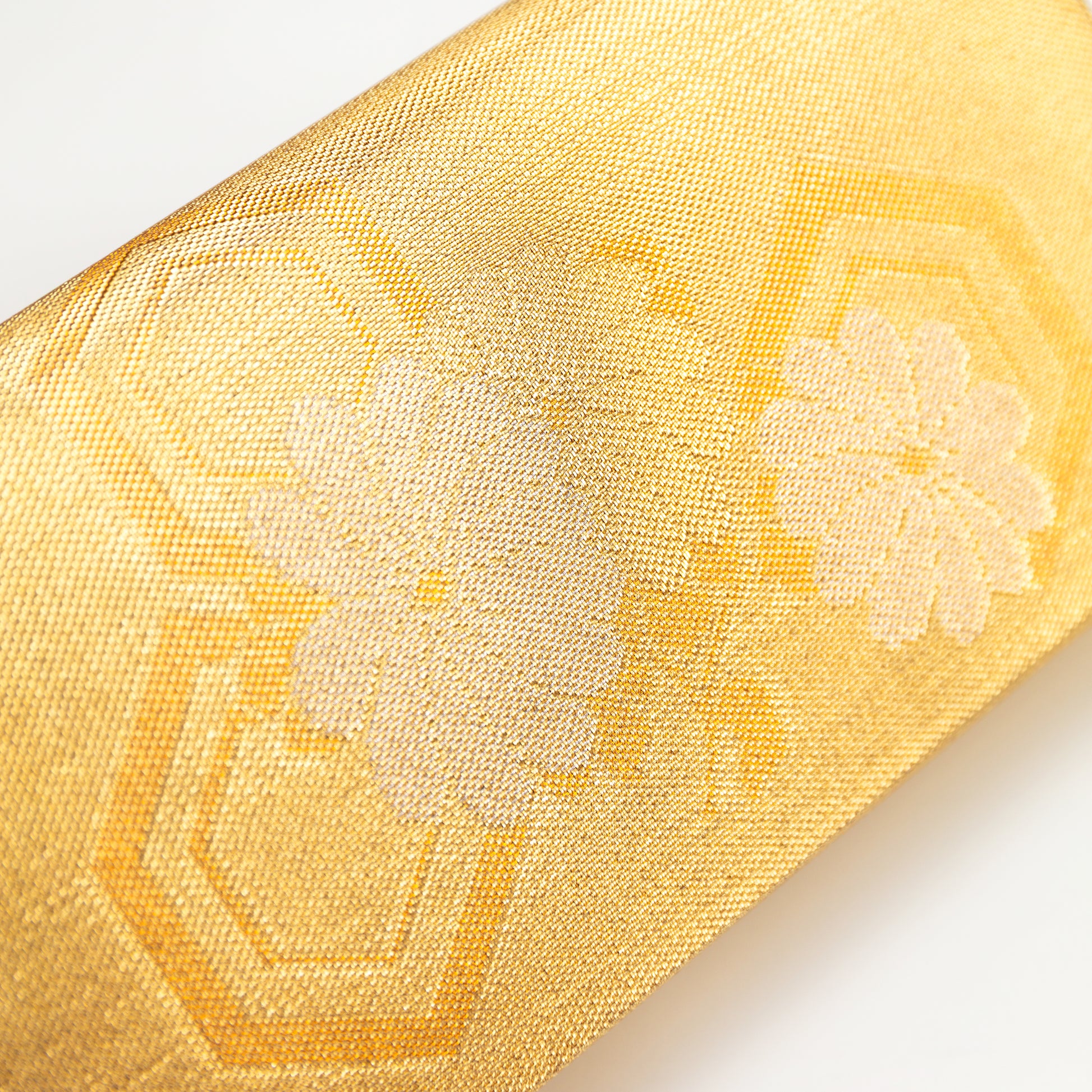 Close-up of a metallic gold silk vintage Japanese clutch bag with floral and hexagon embroidery on a white background