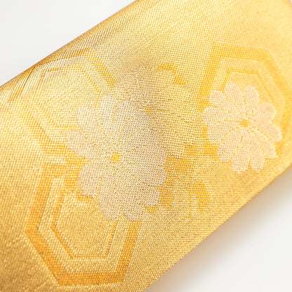 Close-up of a metallic gold silk vintage Japanese clutch bag with floral and hexagon embroidery on a white background