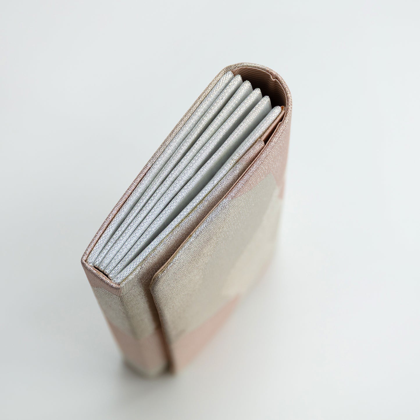 Close-up of a pink vintage silk wallet with a silver side panel on a light gray background