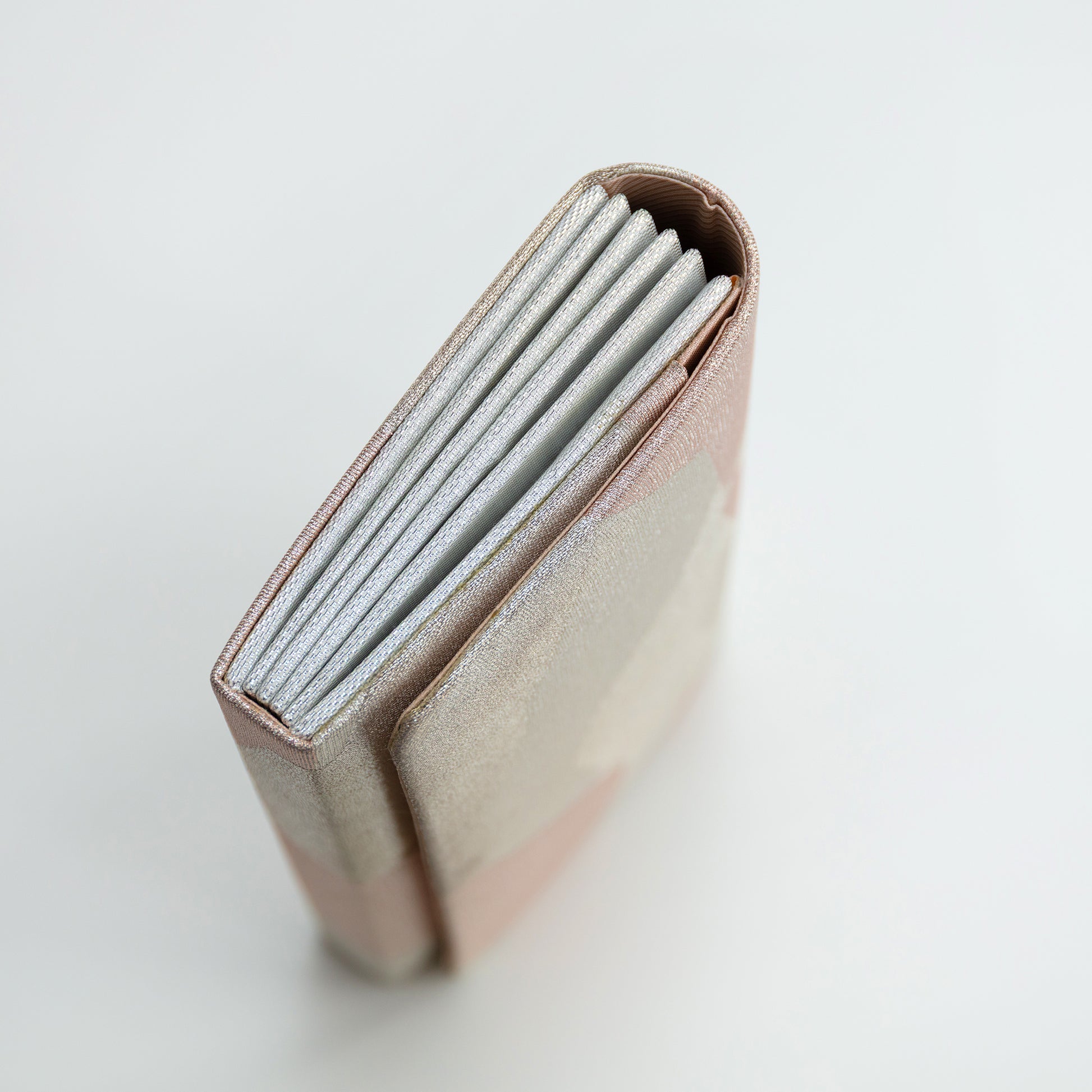 Close-up of a pink vintage silk wallet with a silver side panel on a light gray background