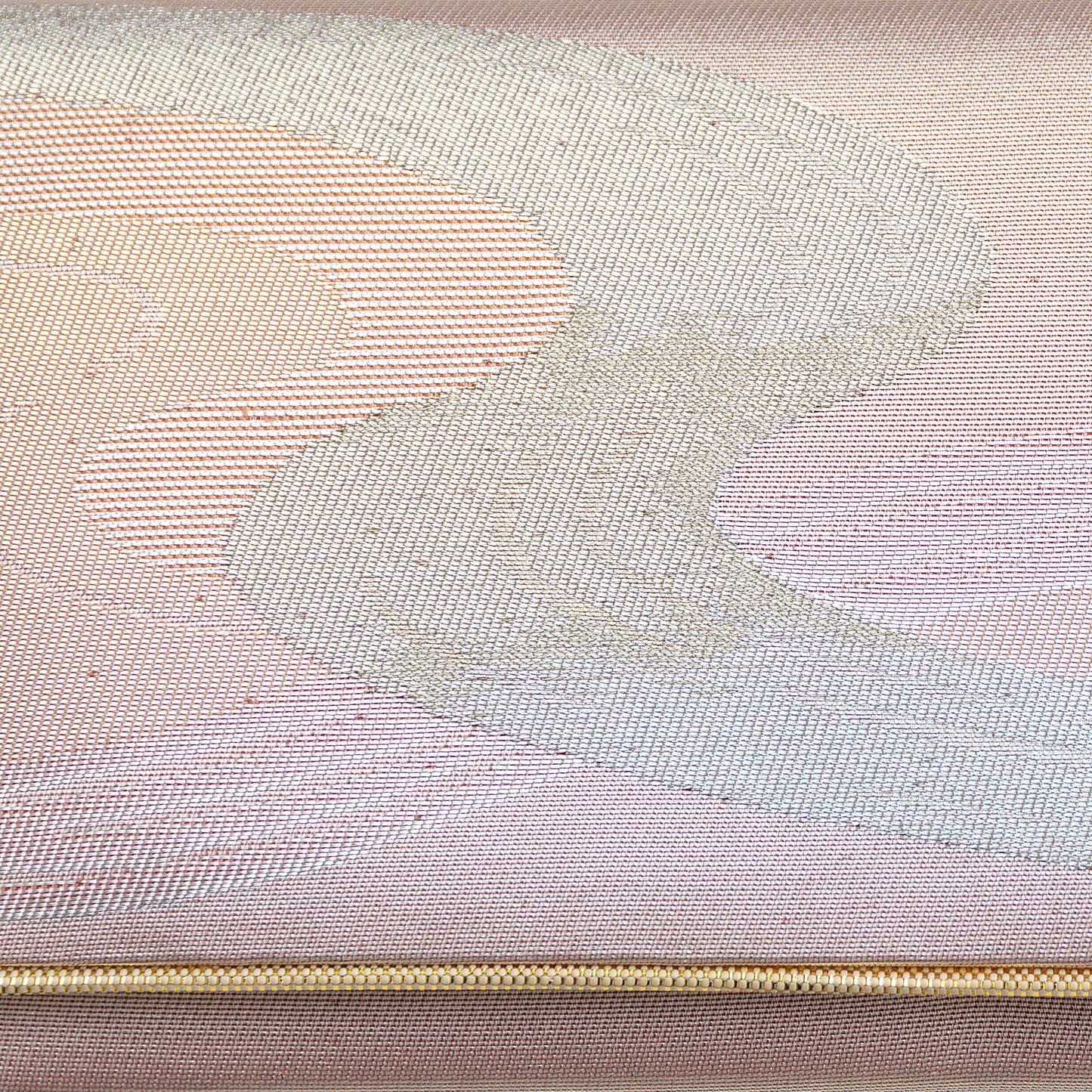 Close up of the woven metallic silk brocade, silver winding river design on iridescent peach pink background with a gold trim.