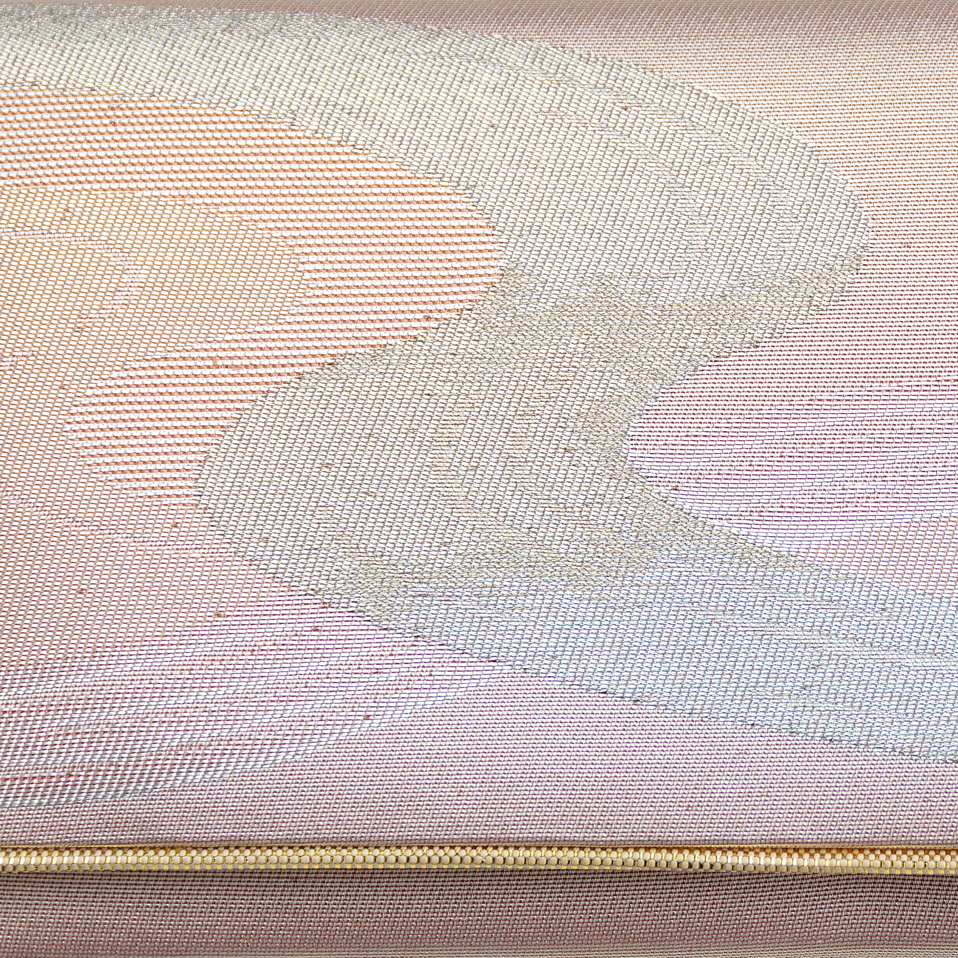 Close up of the woven metallic silk brocade, silver winding river design on iridescent peach pink background with a gold trim.