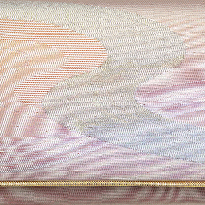 Close up of the woven metallic silk brocade, silver winding river design on iridescent peach pink background with a gold trim.