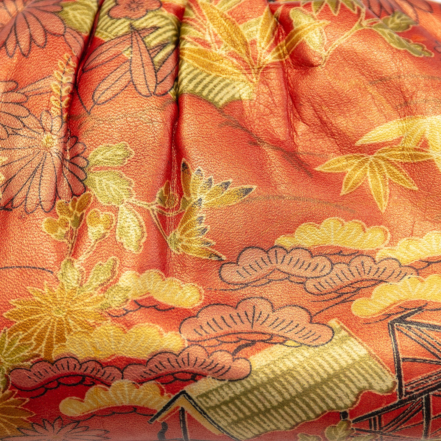 Close-up of a printed vintage leather clutch purse with intricate bamboo, plum and pine patterns (three friends of winter)