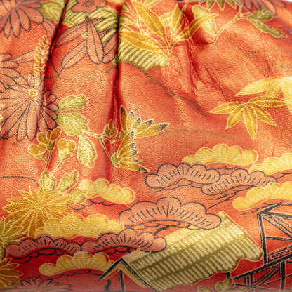 Close-up of a printed vintage leather clutch purse with intricate bamboo, plum and pine patterns (three friends of winter)