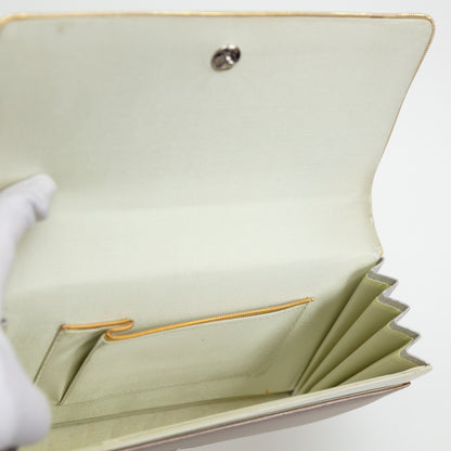 View inside the clutch bag with pale silk lining, gold trim on the internal pocket and the silver stud fastening on white background.