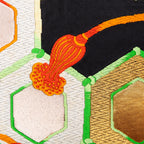 Close-up of gold and black geometric silk pattern highlighting intricate obi textile weave details and rich color contrast.