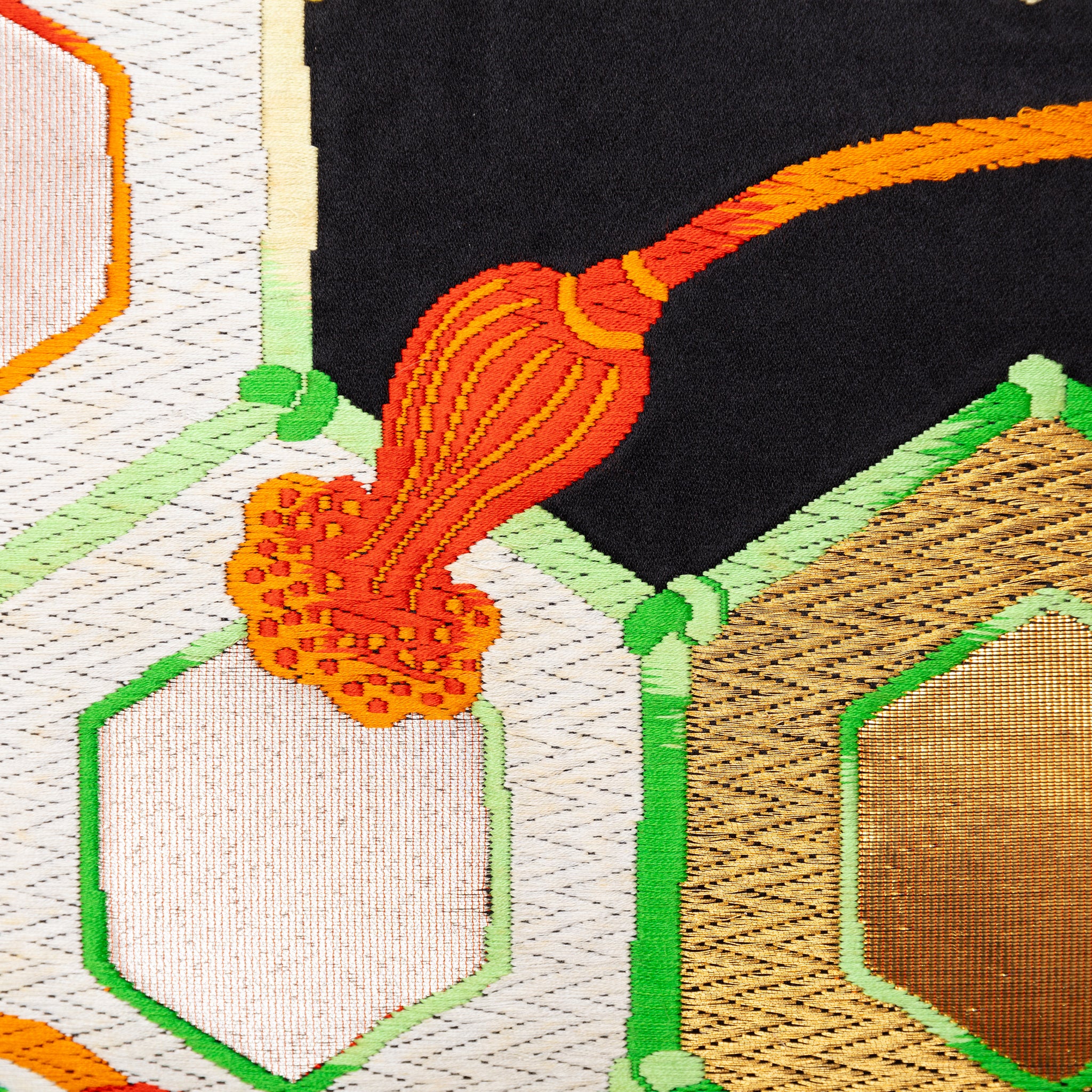 Close-up of gold and black geometric silk pattern highlighting intricate obi textile weave details and rich color contrast.
