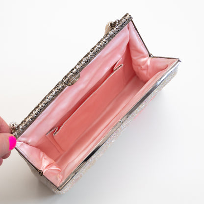 Pink clutch bag with pink silk lining and silver metal decorative trim on a white background