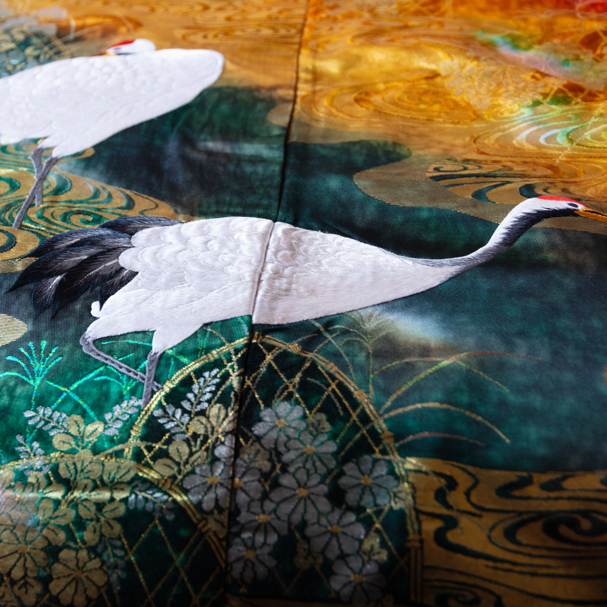 Close-up of multicoloured silk fabric showcasing intricate vintage kimono floral embroidery on the throw's textured surface.