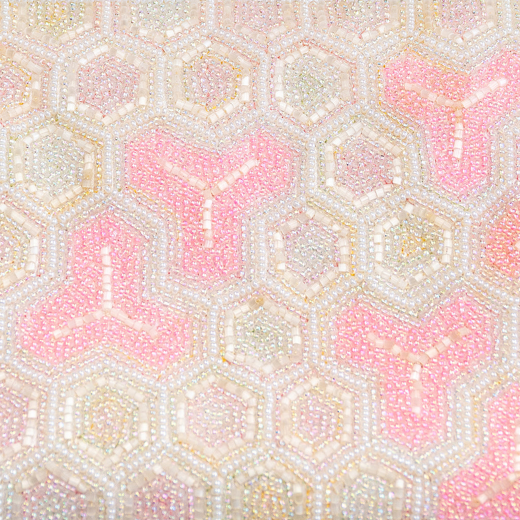 Close-up of intricate pink and white beadwork detailing the clutch’s textured surface and floral pattern from a slightly