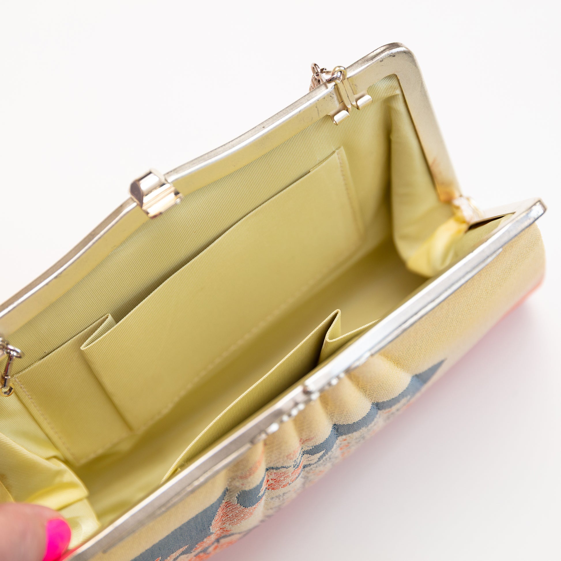 Yellow silk lined vintage 1950s clutch bag with floral pattern on a white background
