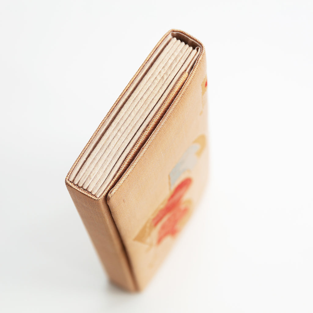 Close-up of gold silk fabric demonstrating intricate orange fan embroidery and subtle shimmering texture on the vintage