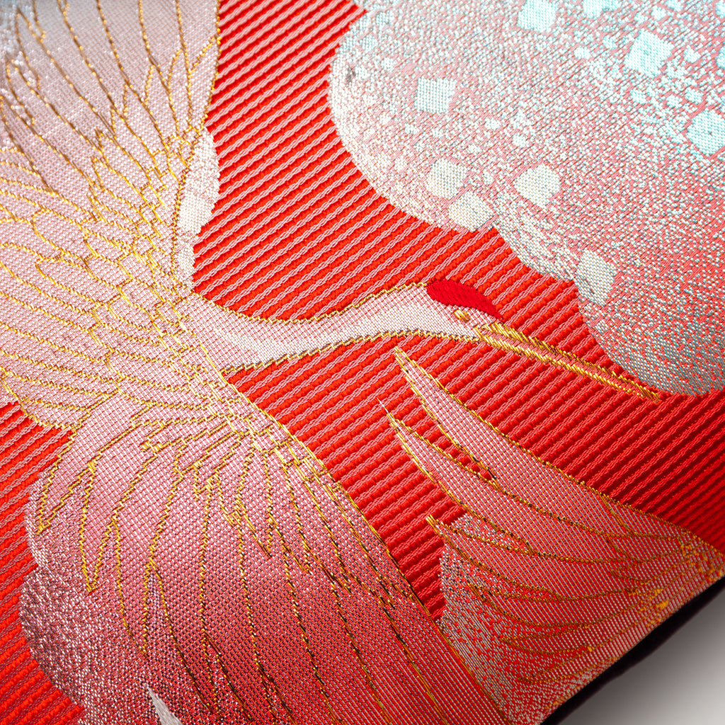 Close-up of the vibrant red silk fabric showcasing intricate crane embroidery and subtle velvet sheen detail.