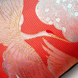 Close up of the wedding kimono silk showing a cranes head and wings in gold thread over red striped silk.