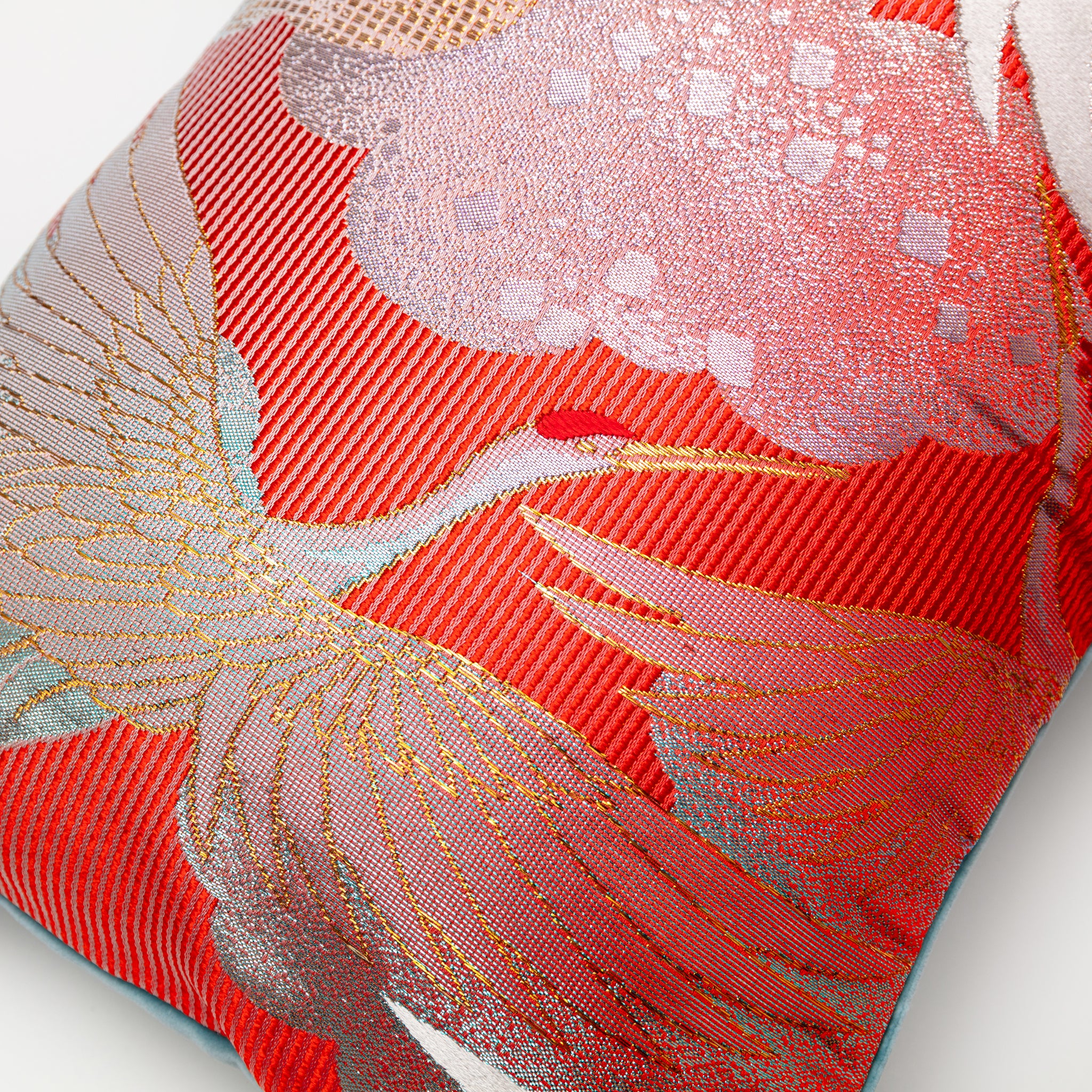 Close-up of the vibrant red cranes embroidered on the blue velvet fabric of the Kimono Silk Bolster Pillow, highlighting