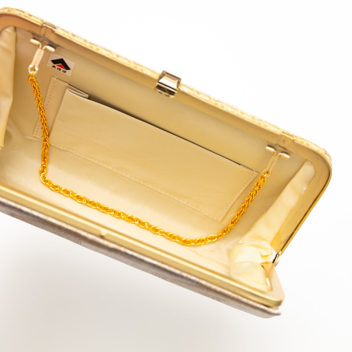 Gold clutch with a chain strap on a white background. View inside the purse showing chain tucked in.