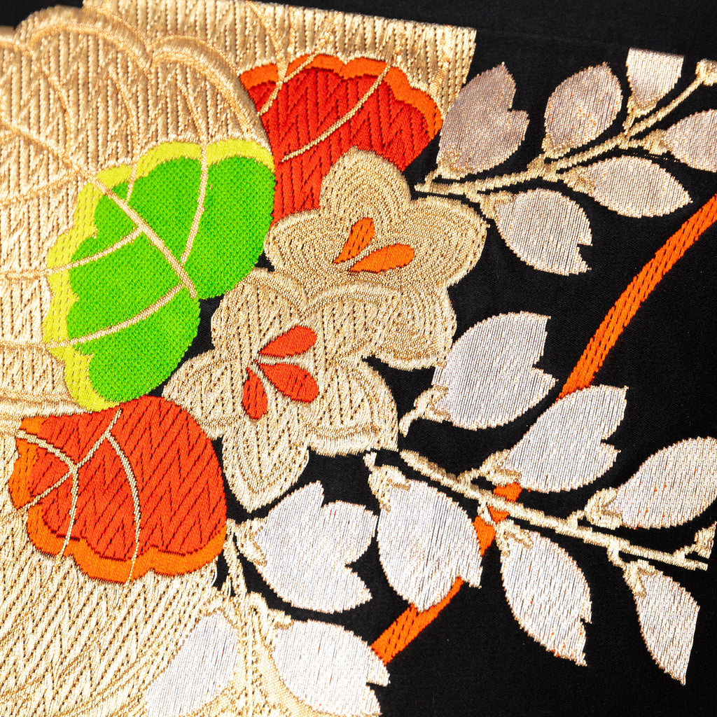 Close-up of floral drum embroidery on black silk fabric highlighting intricate stitching and vivid color details of the