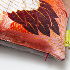 Close-up of the Peachy Red Silk Rising Crane Pillow’s textured silk surface with taupe velvet piping visible from an
