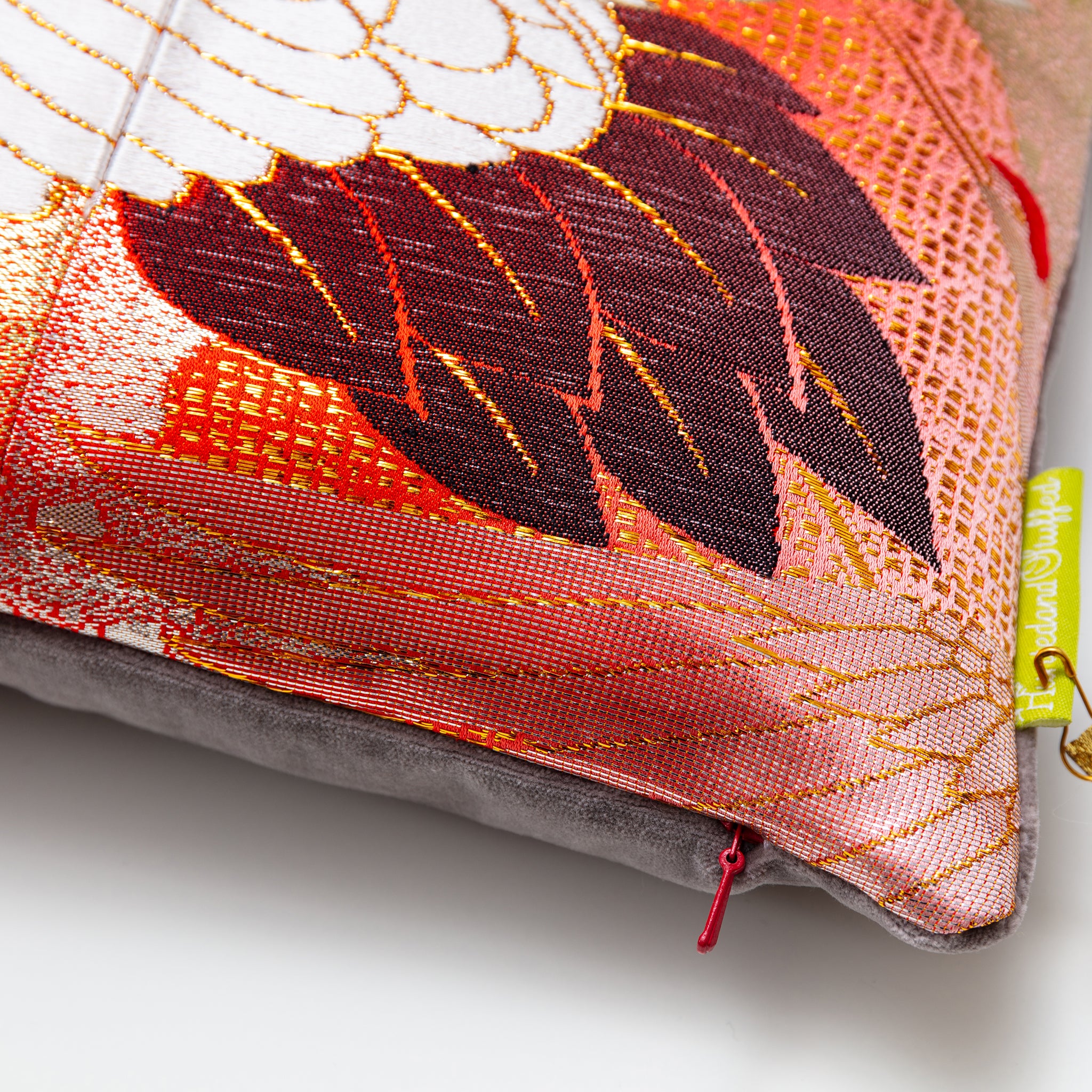 Close-up of the Peachy Red Silk Rising Crane Pillow’s textured silk surface with taupe velvet piping visible from an