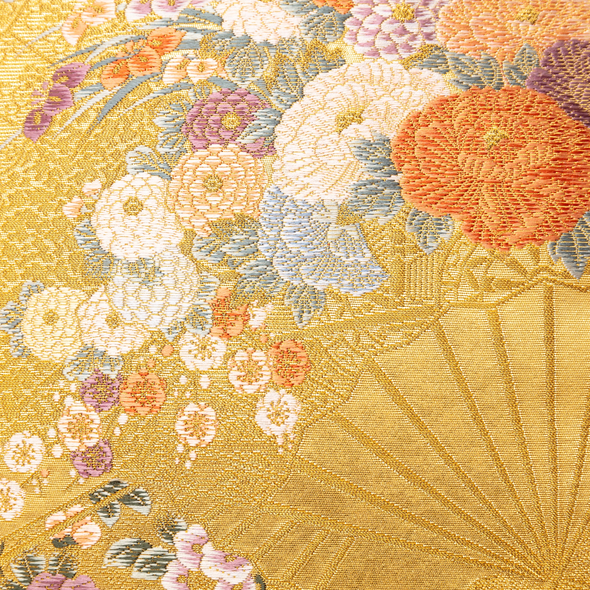 Close-up of gold silk fabric featuring intricate embroidery of birds, fans, and flowers with visible purple velvet backing