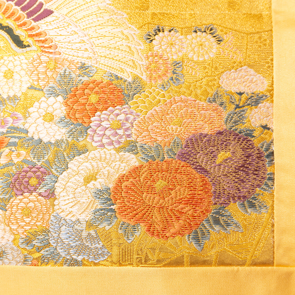Close-up of intricate gold silk embroidery on the Golden Phoenix Cushion’s obi with detailed floral accents and textured