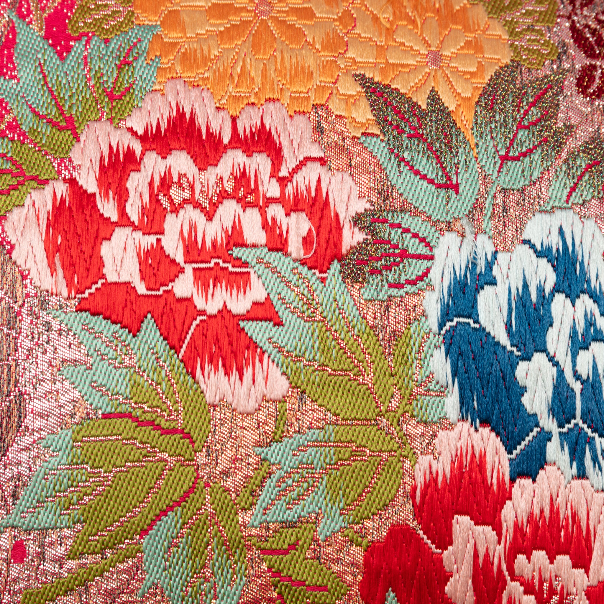 Close-up of the intricate embroidered cranes and blooming flowers on the lilac velvet backdrop of the red kimono bolster