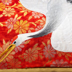 Close-up of intricate red and gold silk embroidery showcasing flying crane motif on bolster pillow edge.