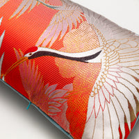 Detail of bolster cushion showing a cranes head and open wings in white, the concealed zip matching the pale blue velvet reverse of the pillow.
