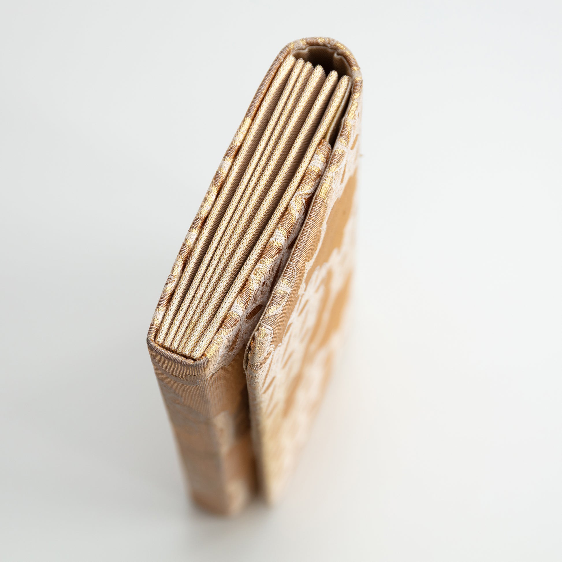 Side view of the gold silk clutch bag on a white background.
