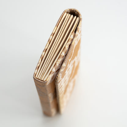 Side view of the gold silk clutch bag on a white background.
