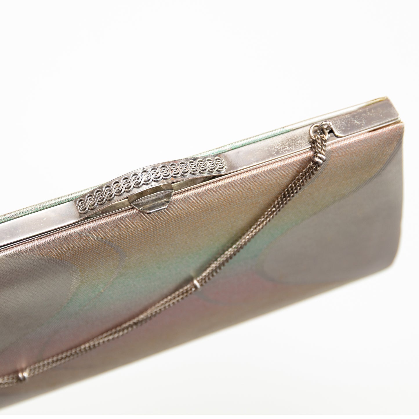 Metallic iridescent clutch with decorative silver chain and clasp on a white background