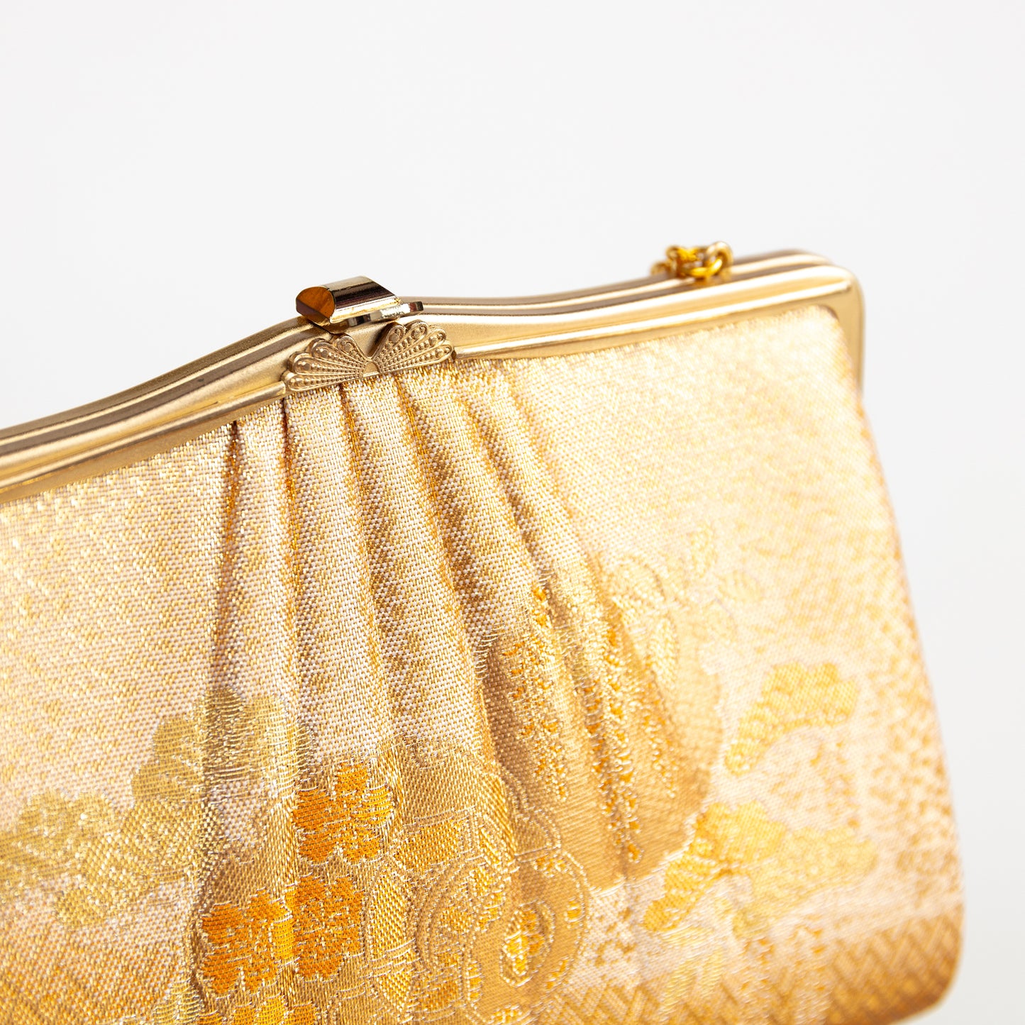 Gold clutch bag with floral patterns on a white background. Vintage Japanese evening bag circa 1970s